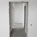 Interior view of a simple white corridor in an unfinished building, showing raw construction details.
